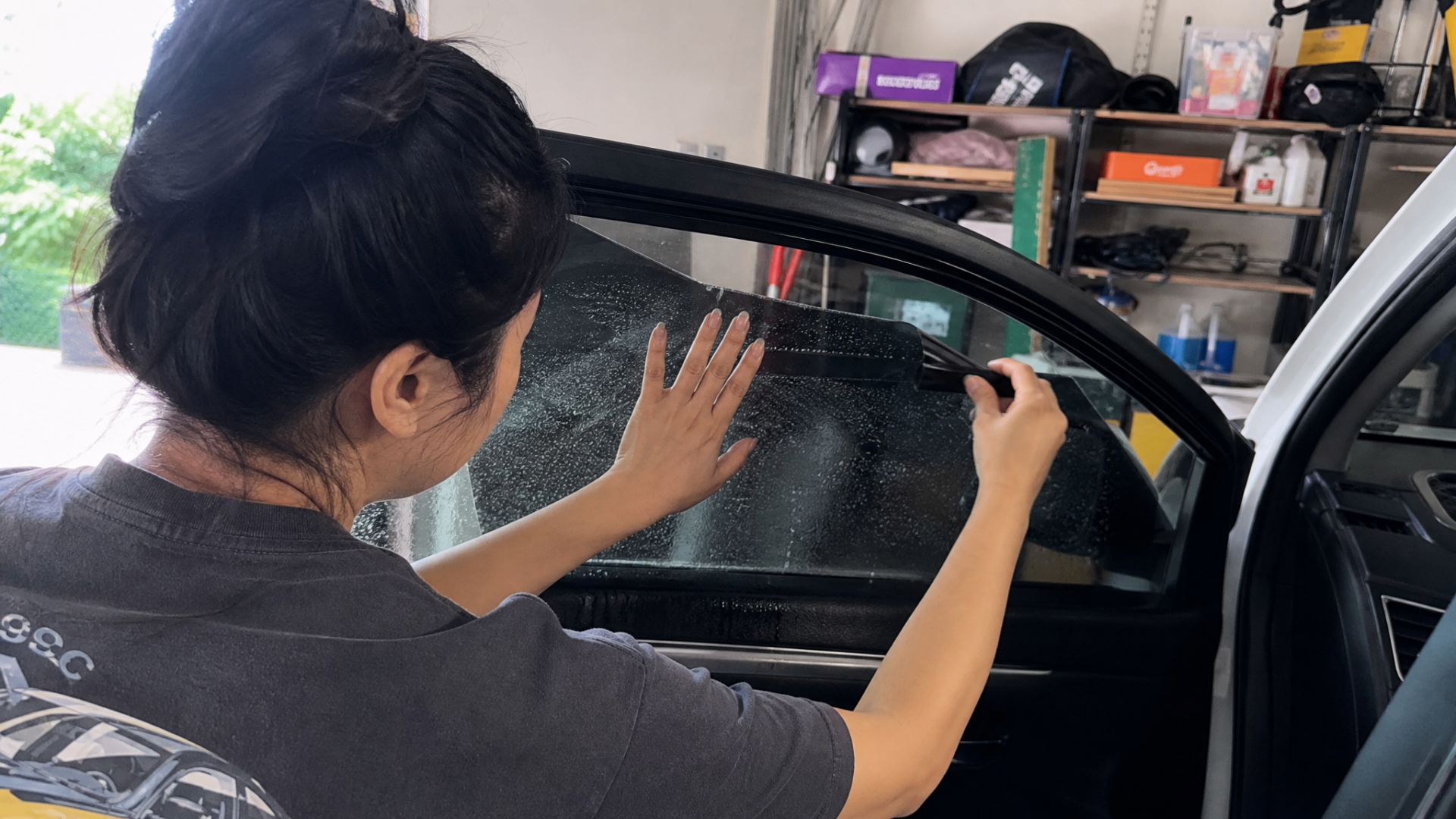 Mei squeegeeing water out from under precut ceramic film on the front door of a Ford Focus.