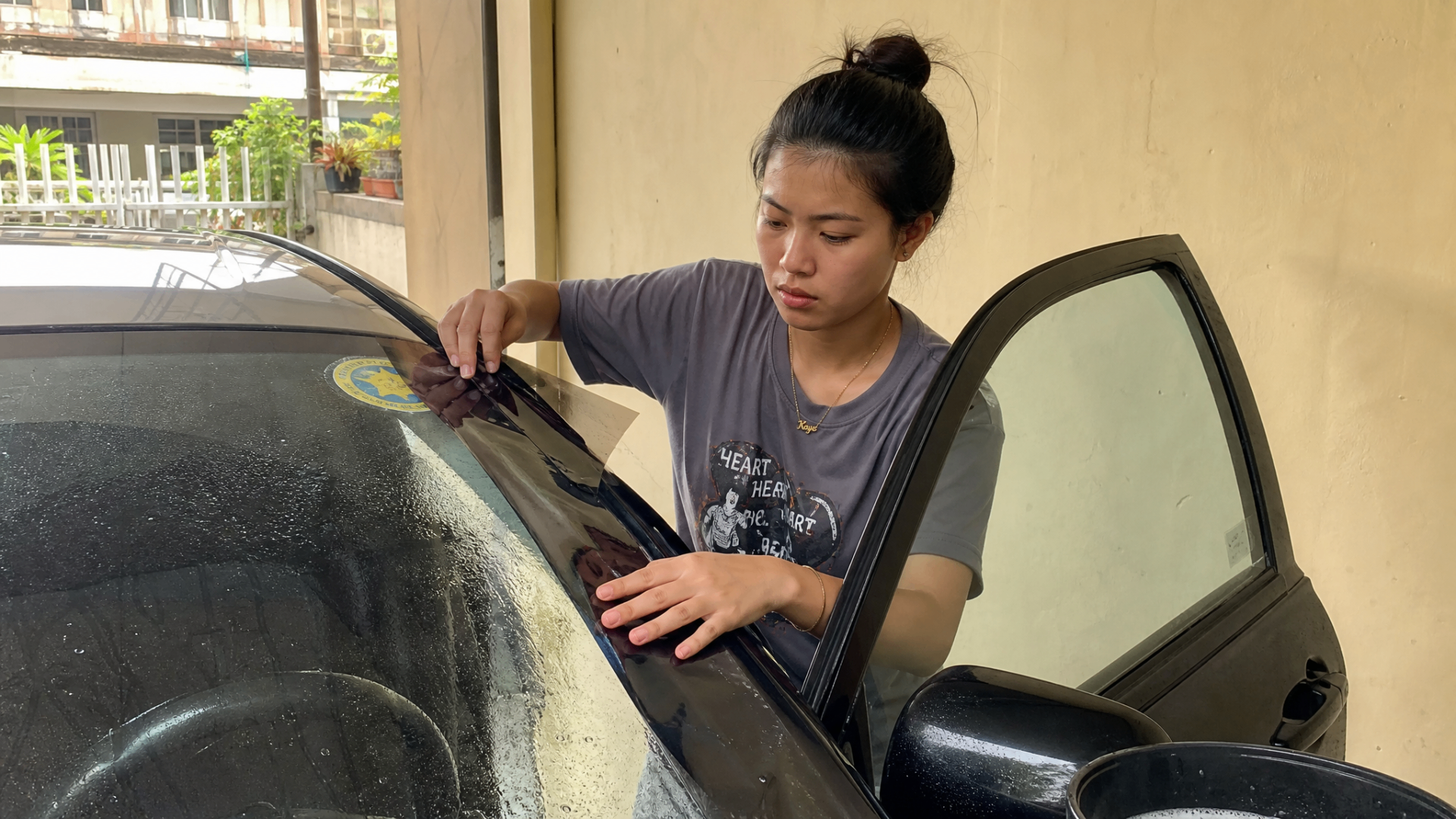 Noa aligning a strip of window film along the top edge of a windshield-side door glass.
